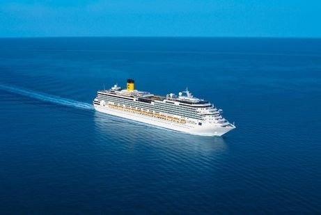 Aerial view of a costa Toscana cruise large, white cruise ship sailing through calm, deep blue ocean waters under a clear sky, conveying a sense of peacefulness and adventure.