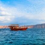 Tour boat cruising through the fjords of Musandam with rugged mountains in the background
